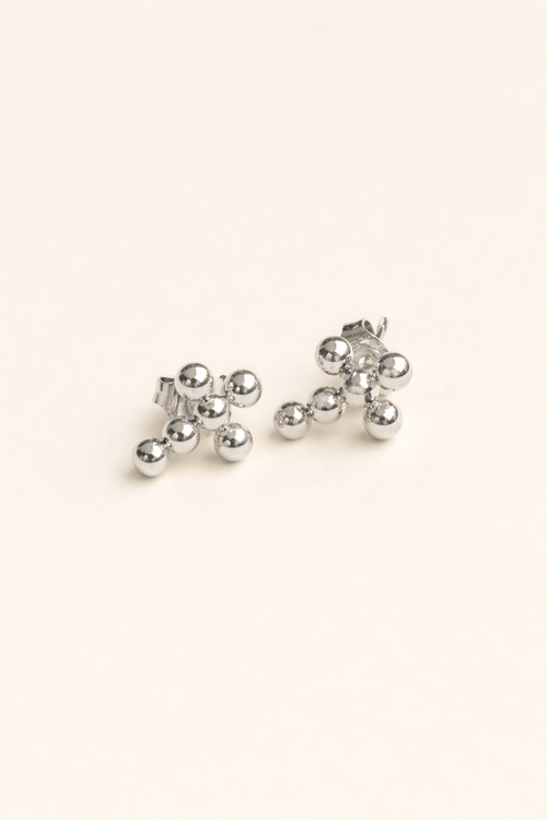 Pair of silver cross earrings on a light beige background