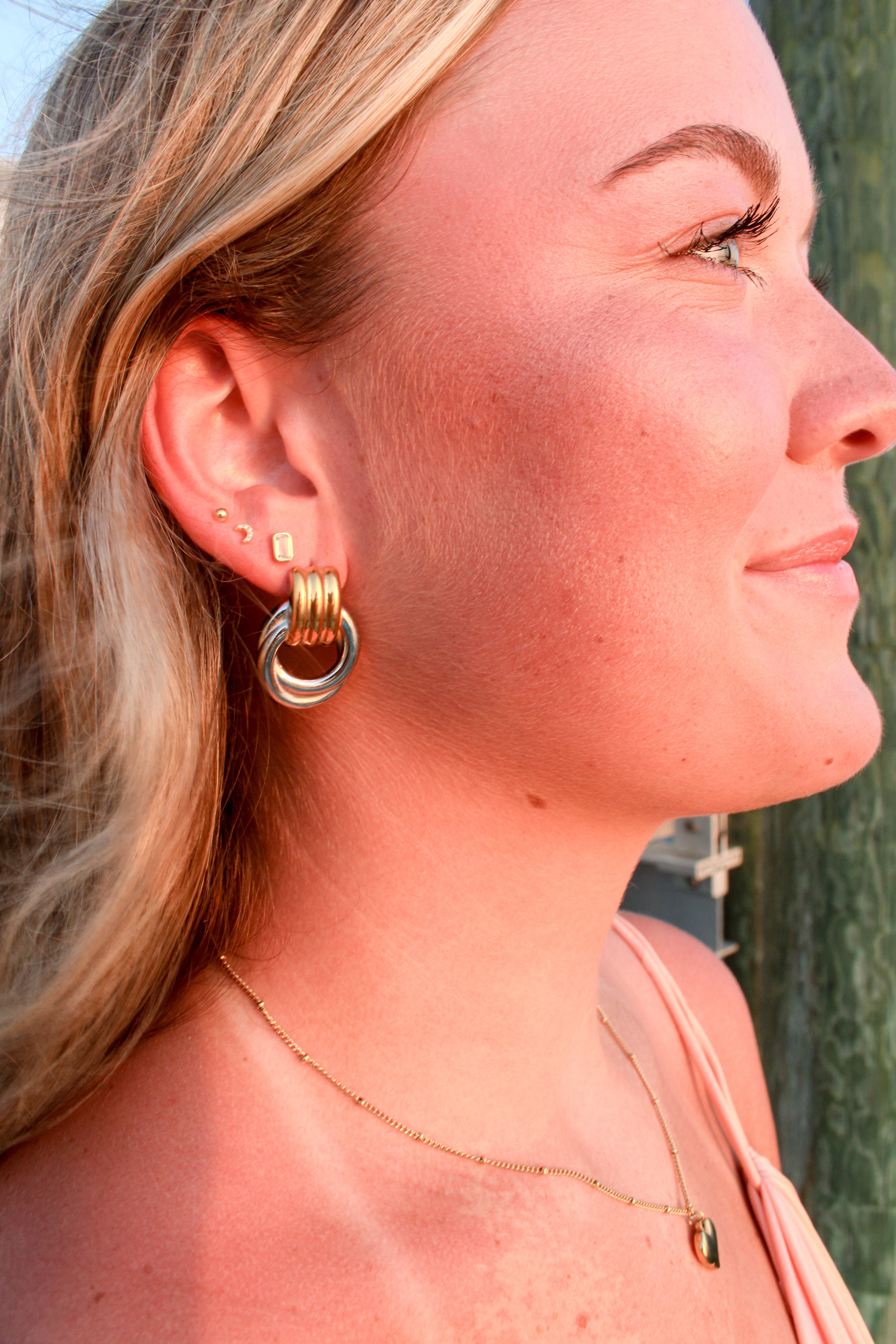 Woman wearing mix metal vintage style stud earrings and necklace with a blurred background