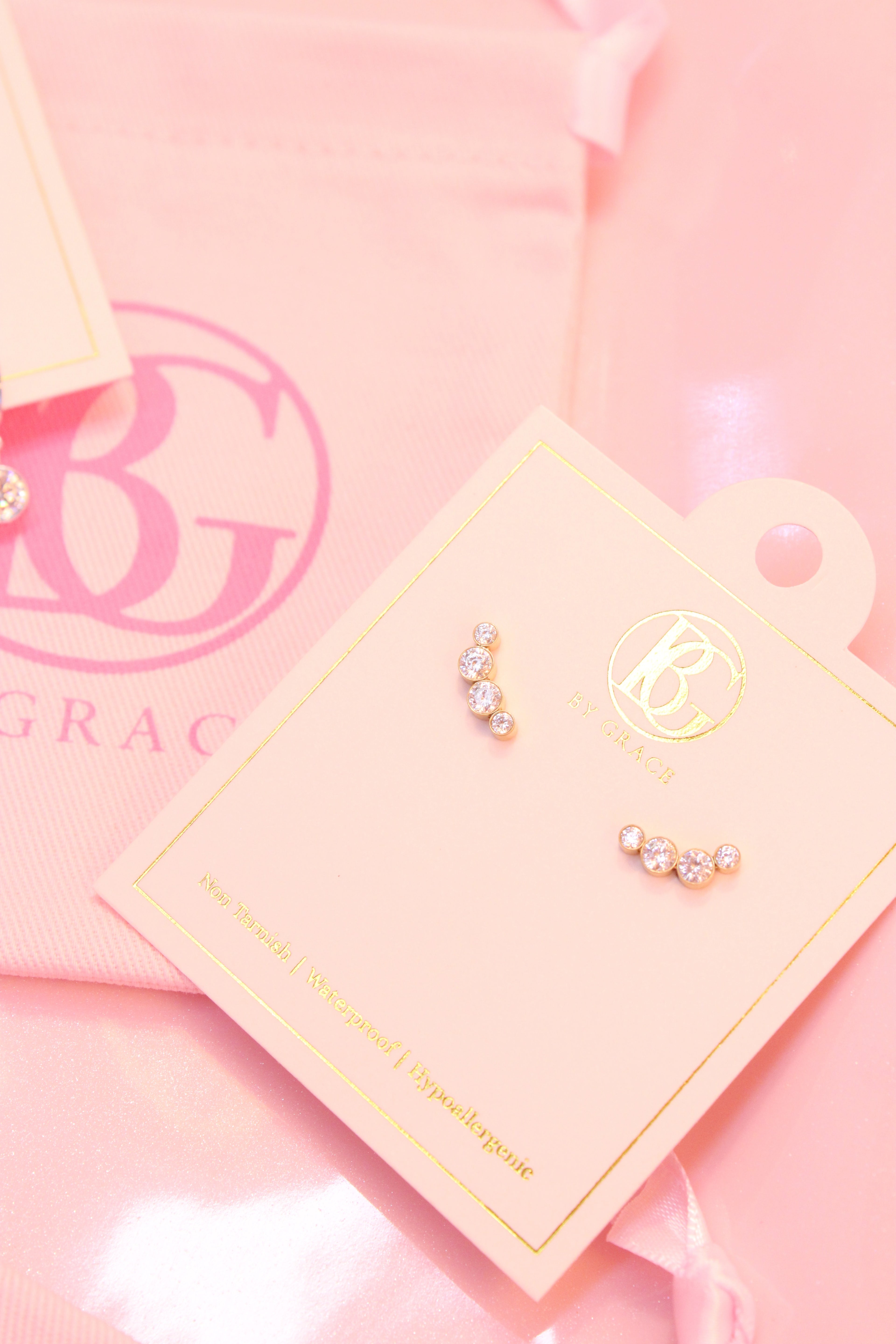Pair of earrings on a branded card with a pink background