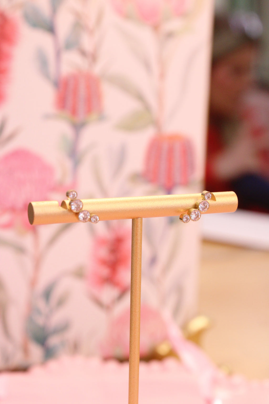 multi diamond earrings on a stand against a floral background