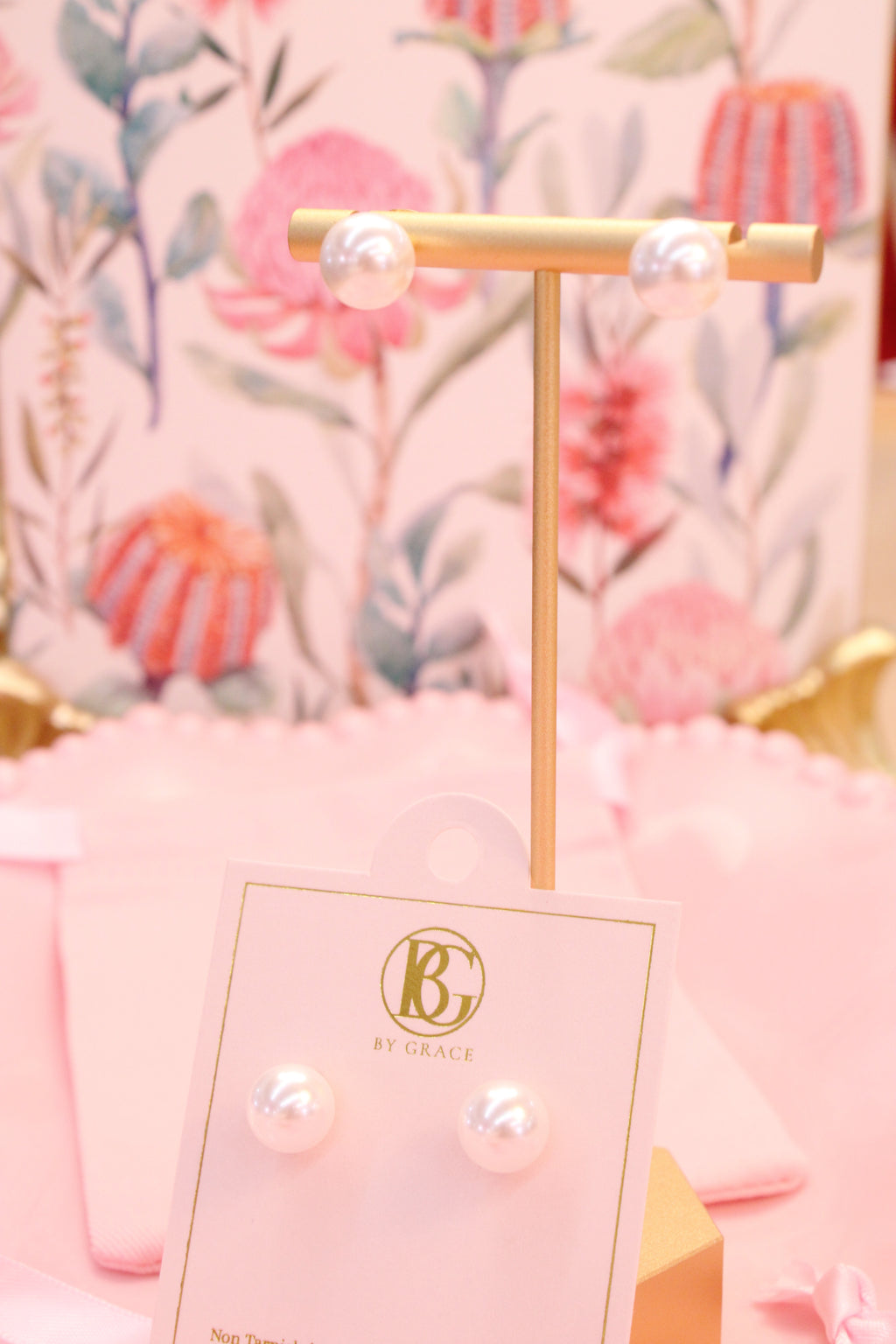Pair of pearl earrings on a gold stand with a floral background