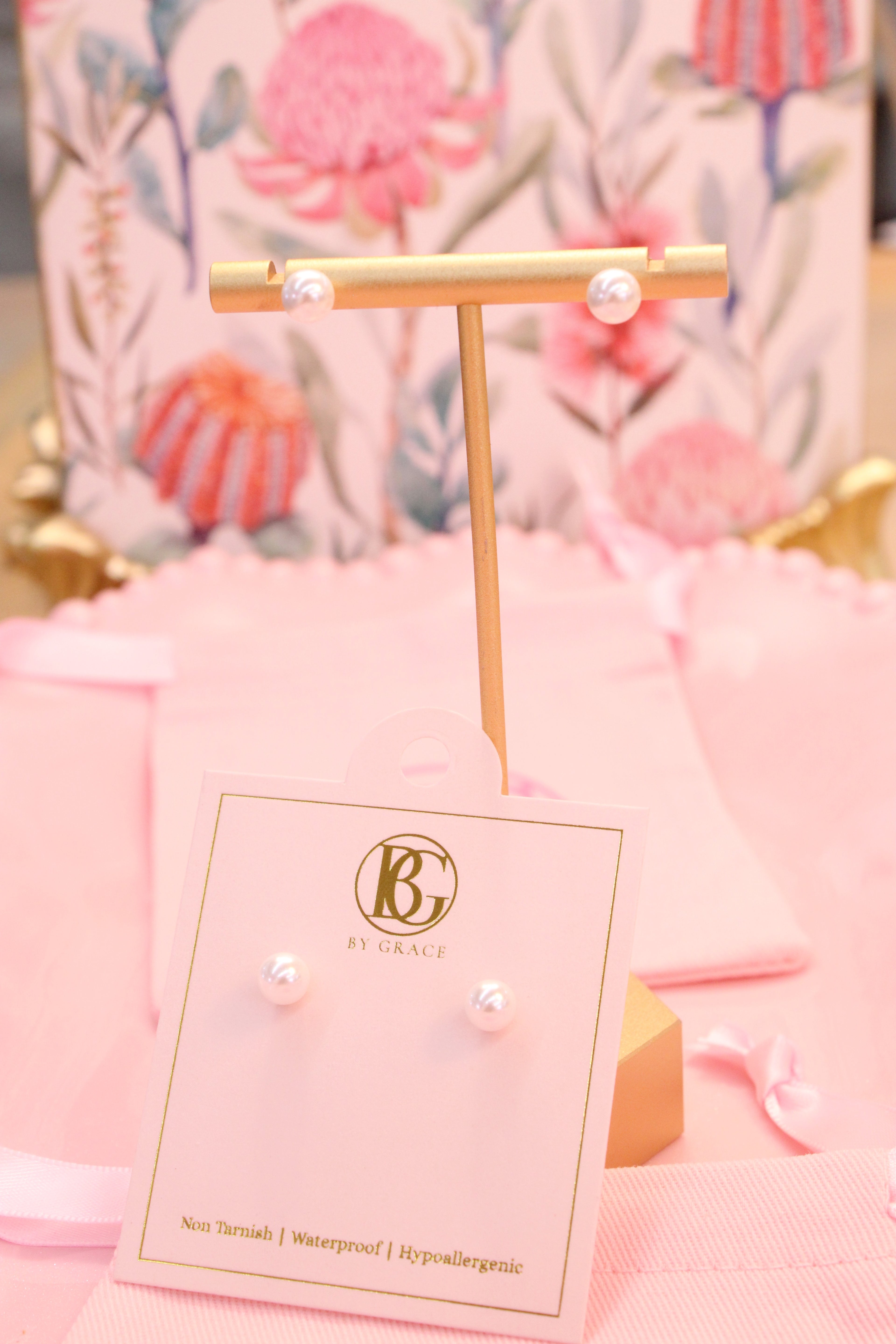 Pair of pearl earrings on a display card with a decorative background