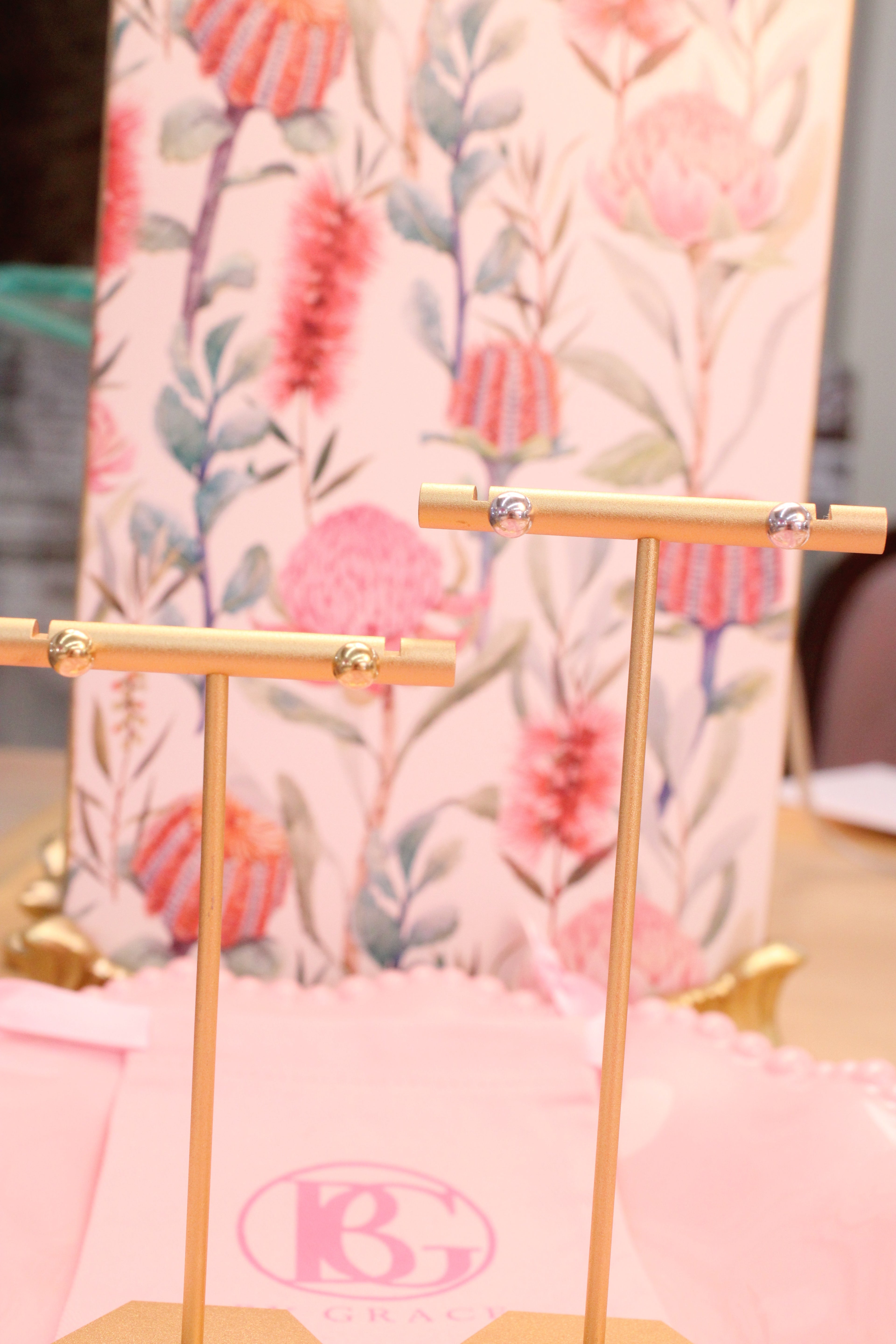 Floral-patterned background with ball earrings on gold stand