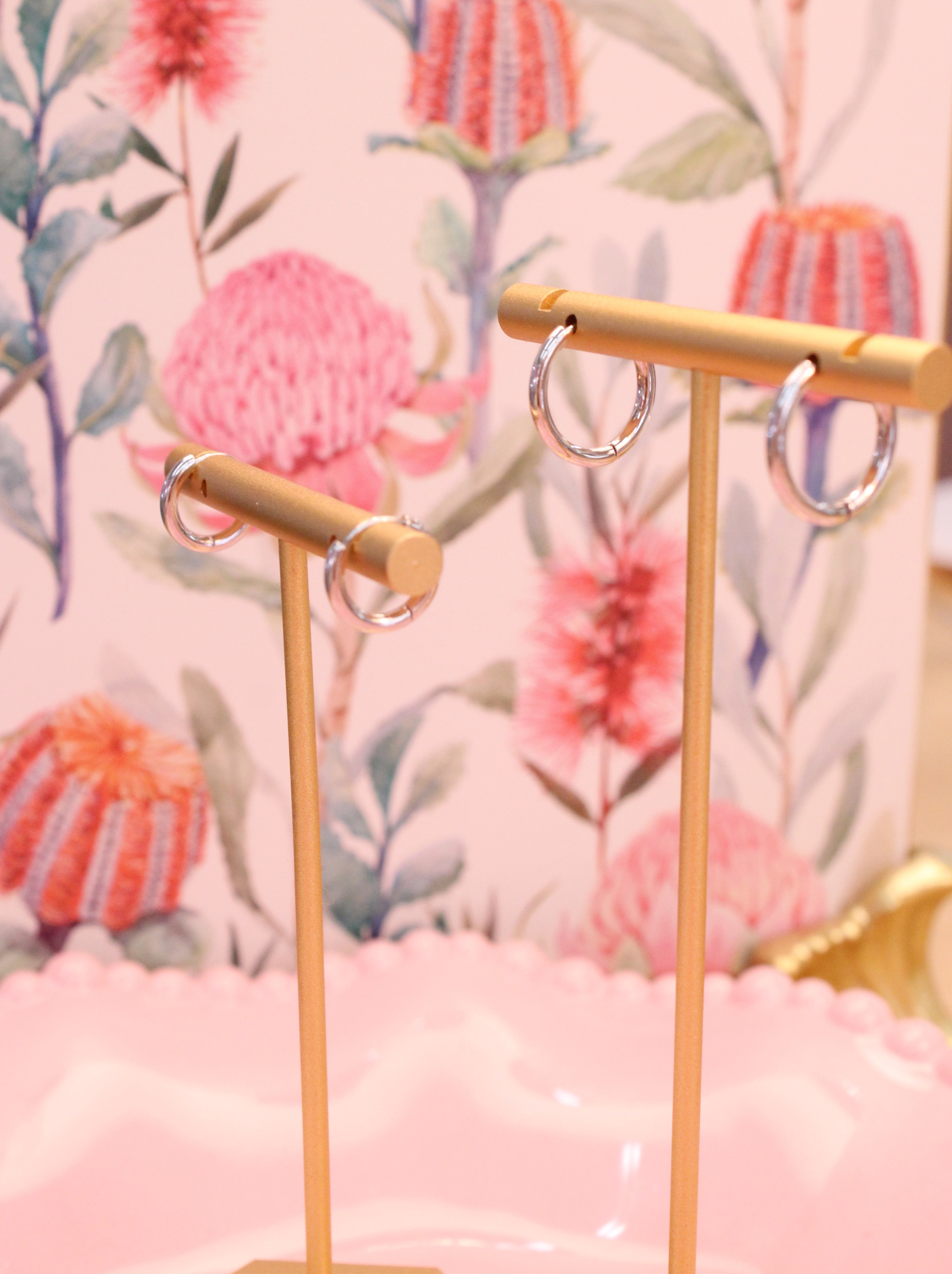 Gold earring stand with earrings on a floral background