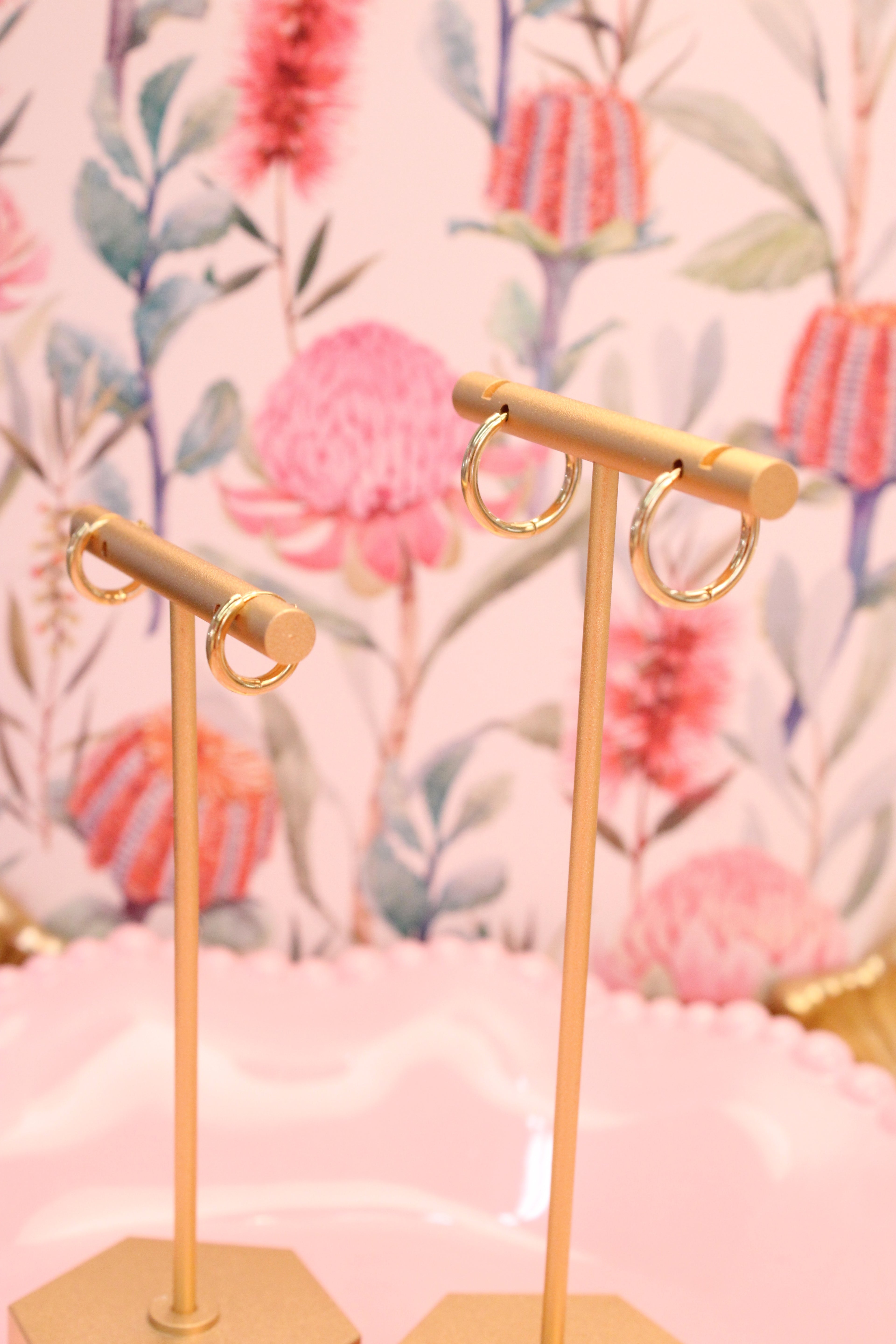 Gold earring stand with earrings on a floral background